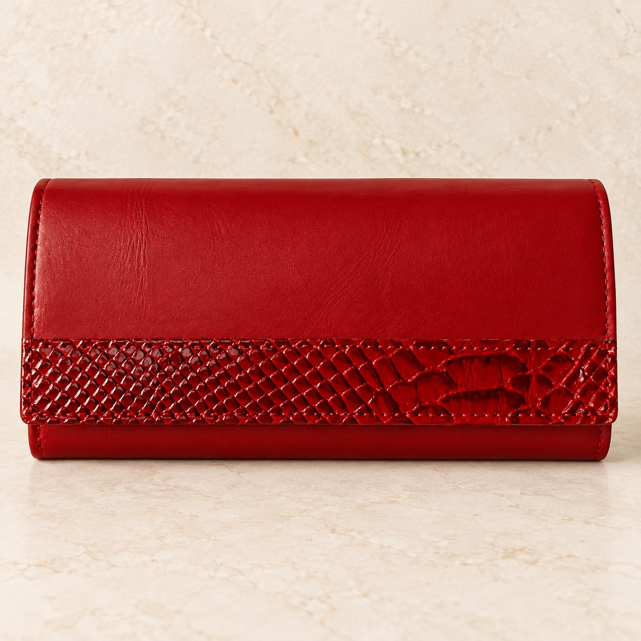 Red leather clutch wallet photographed on a cream stone surface