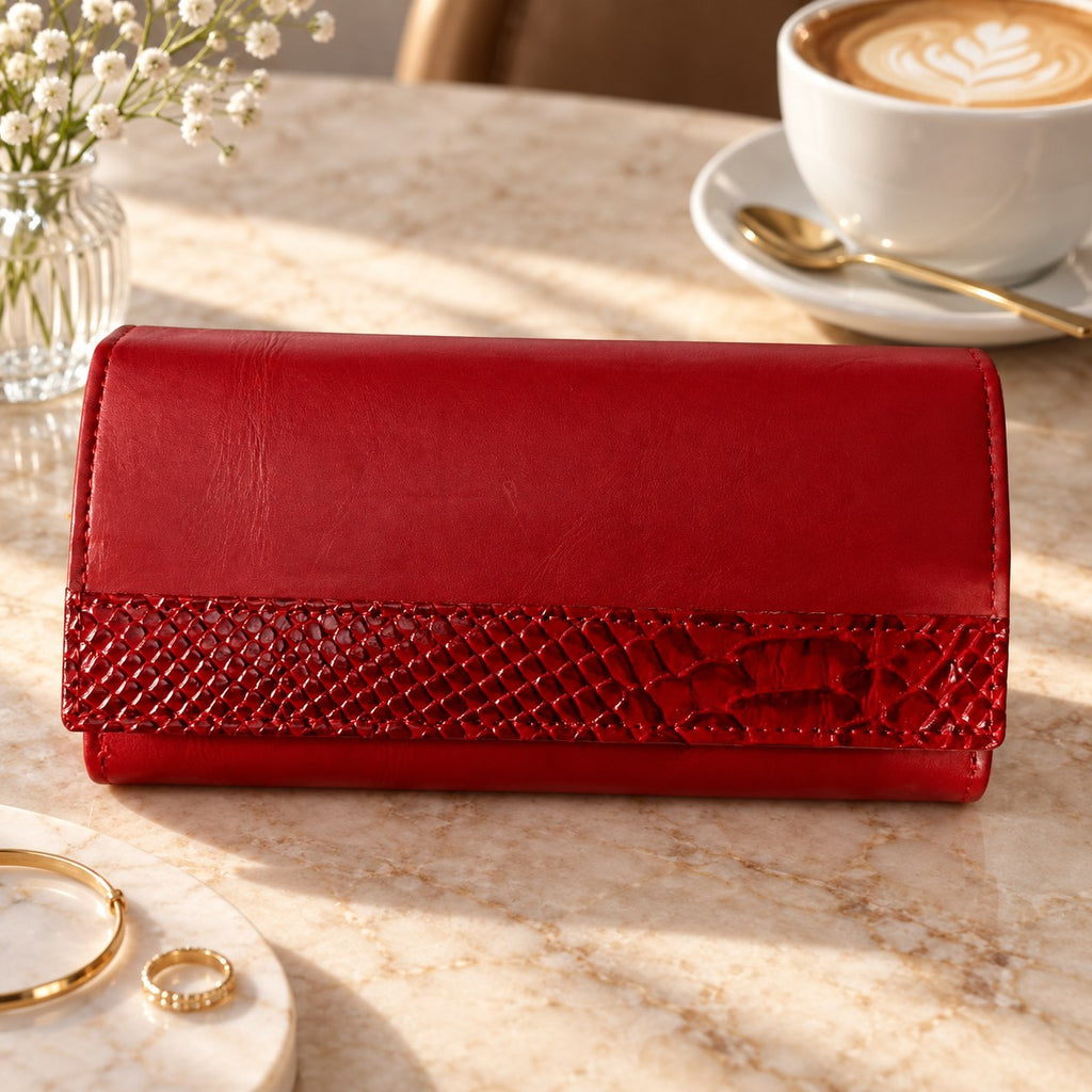 Red leather clutch wallet on a marble table beside a coffee cup