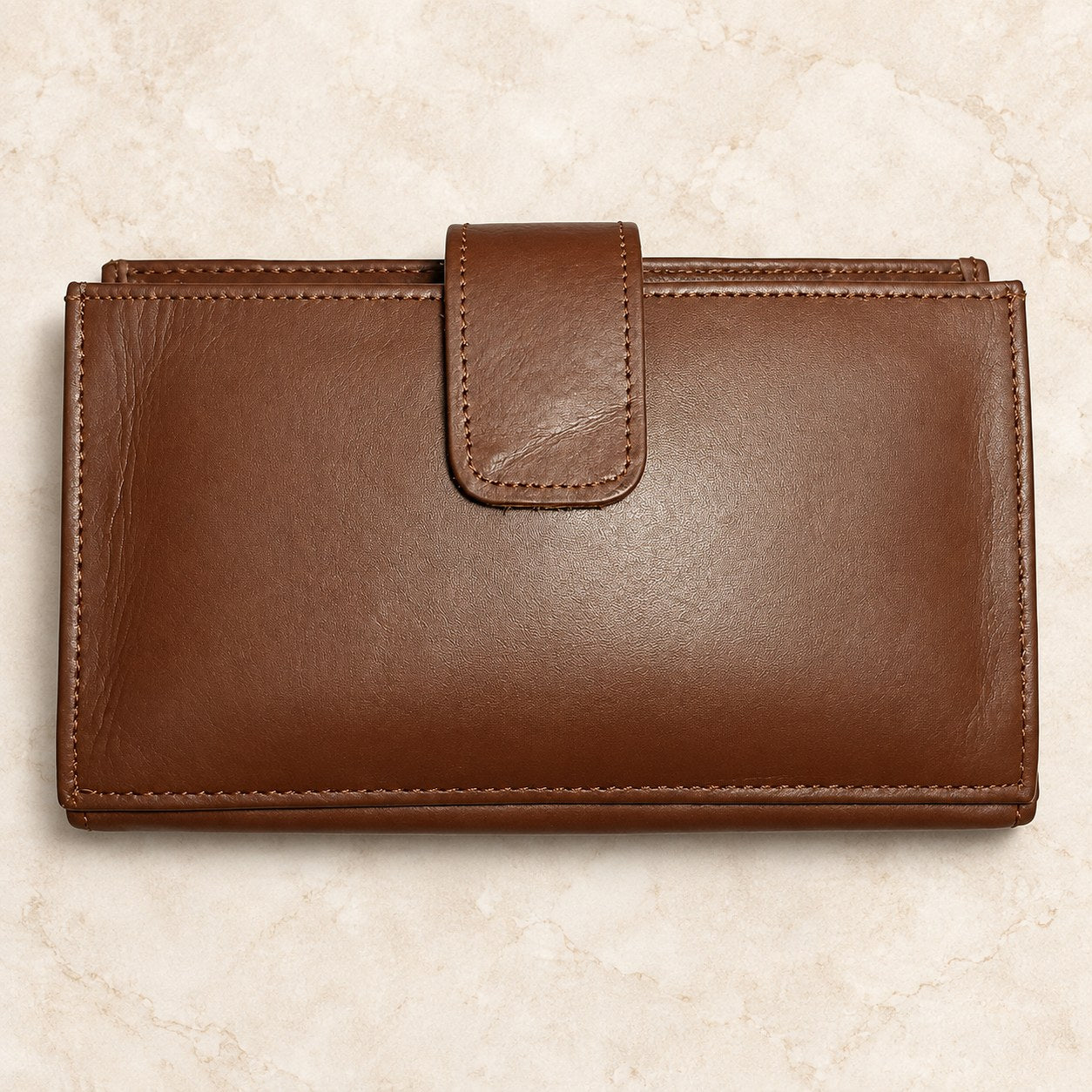 Brown leather long wallet displayed on a cream stone background