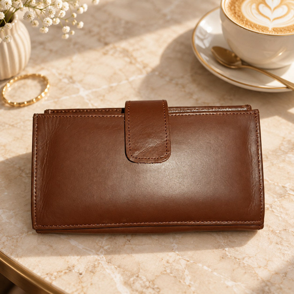 Brown long wallet on a marble cafe table beside a coffee cup