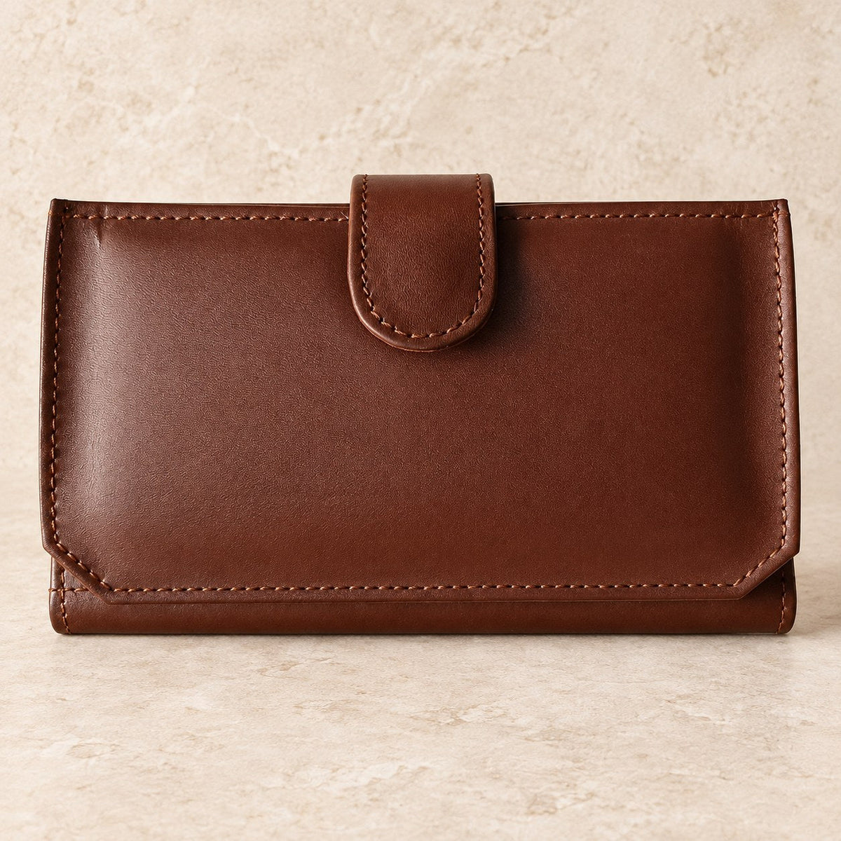 Brown leather flap wallet displayed on a cream stone background