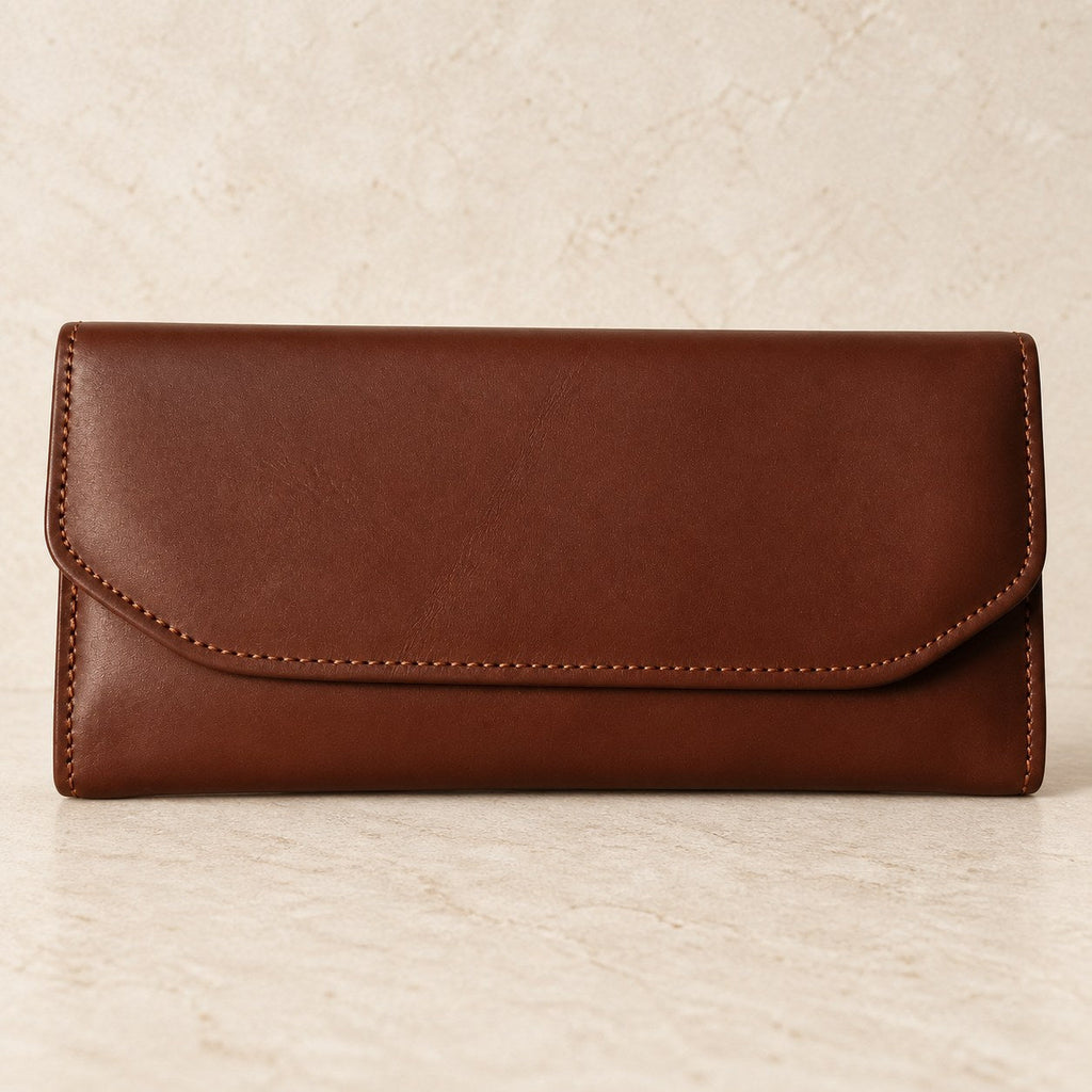 Brown leather envelope wallet photographed on a cream stone surface