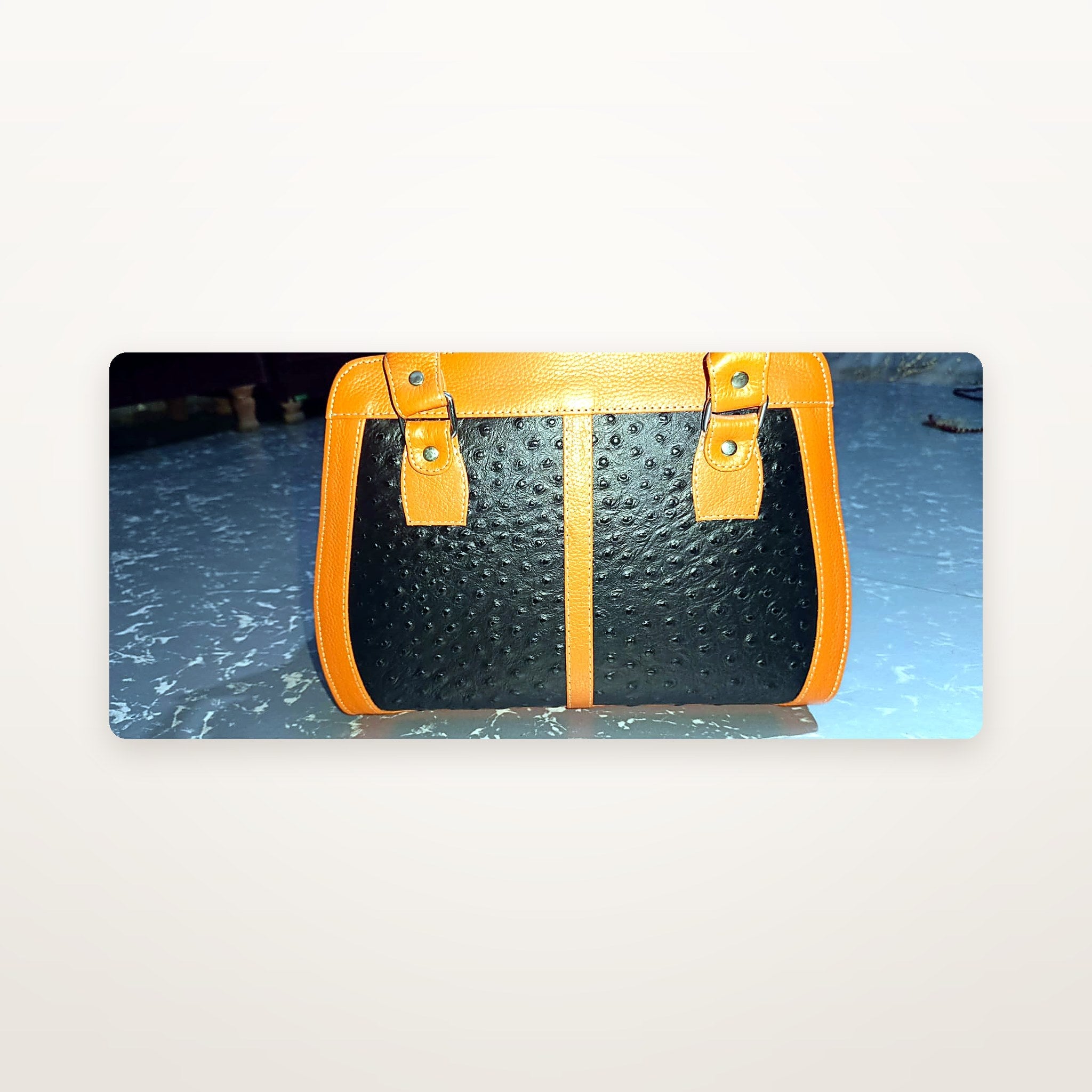Orange and black leather handbag with top zip open