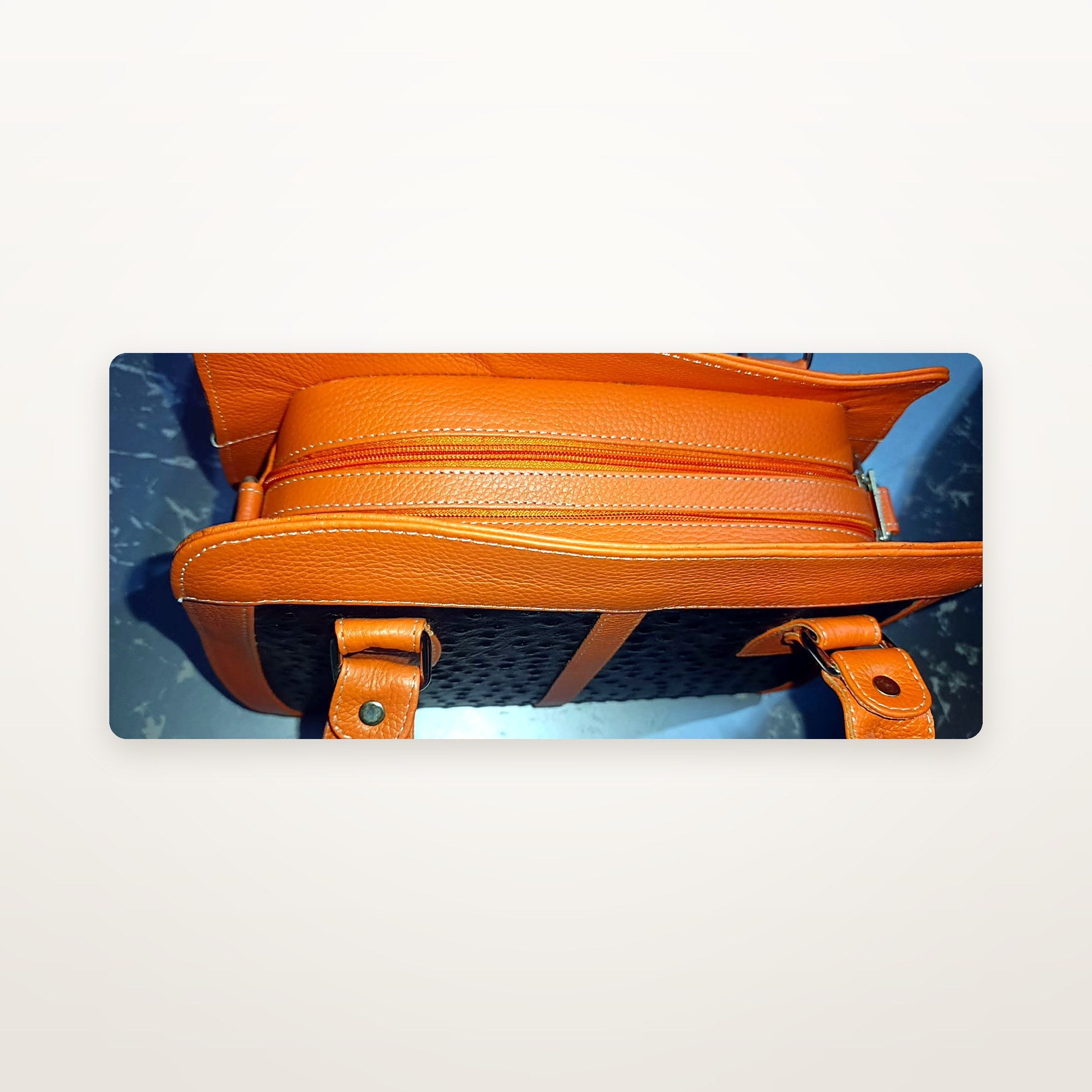 Orange and black leather handbag top view showing handles and zip