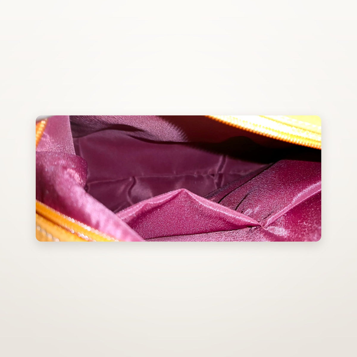 Handbag interior showing fuchsia satin lining and zip pocket
