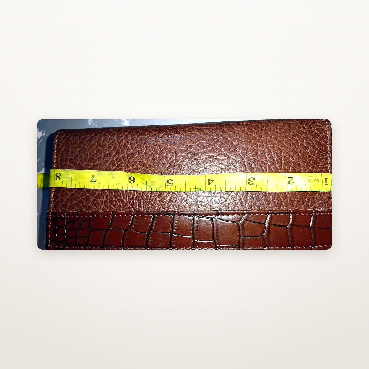 Brown croc-embossed leather long wallet with tape measure showing width