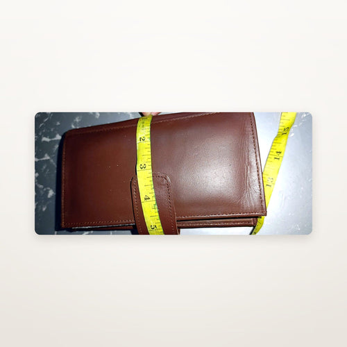 Chestnut leather trifold wallet with tape measure showing size