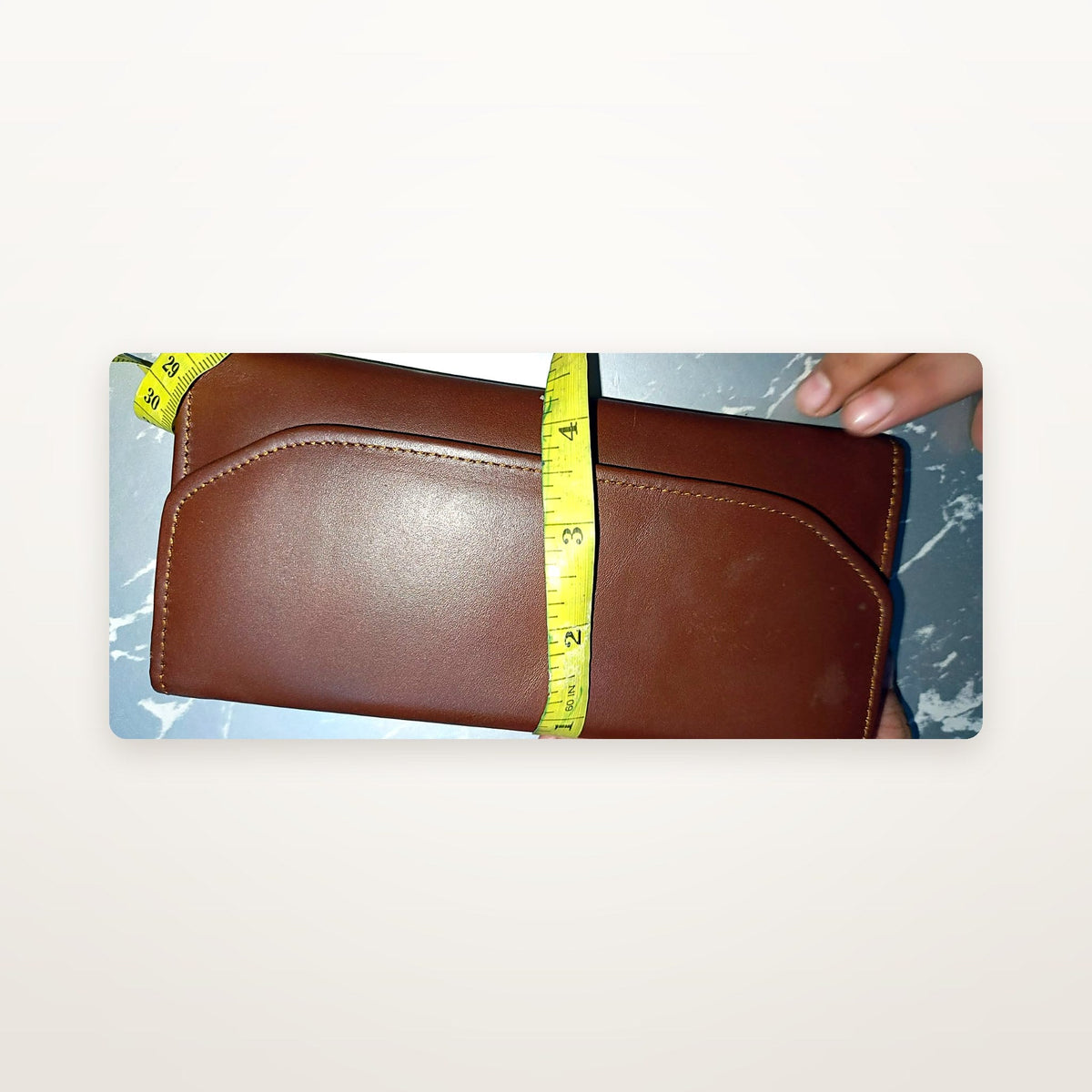 Chestnut leather trifold wallet closed, angled with size reference